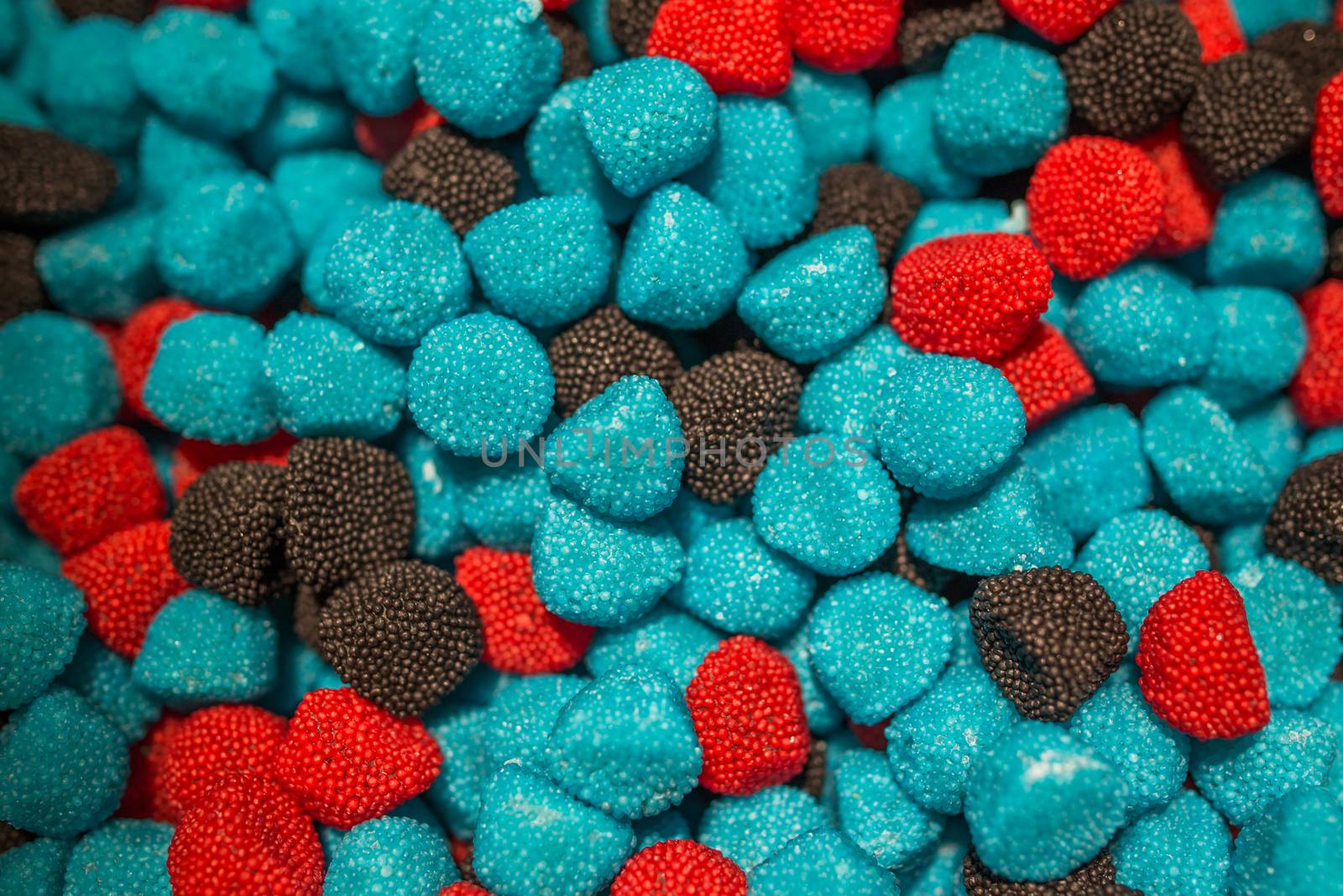 Blue black and red jelly candies in the form of raspberries and blackberries.