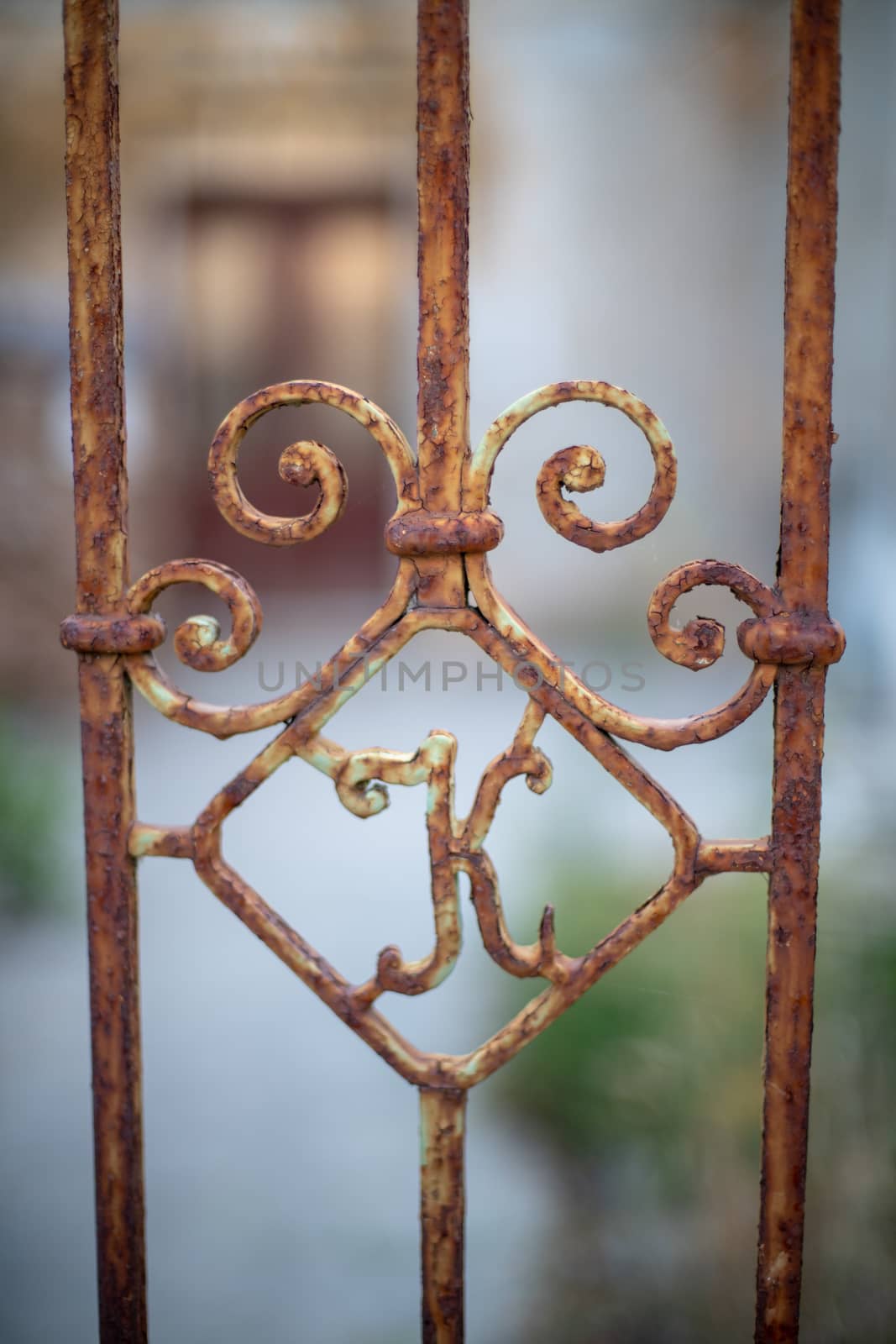 Old rusty iron gate with letter K, abandoned house in background by asafaric