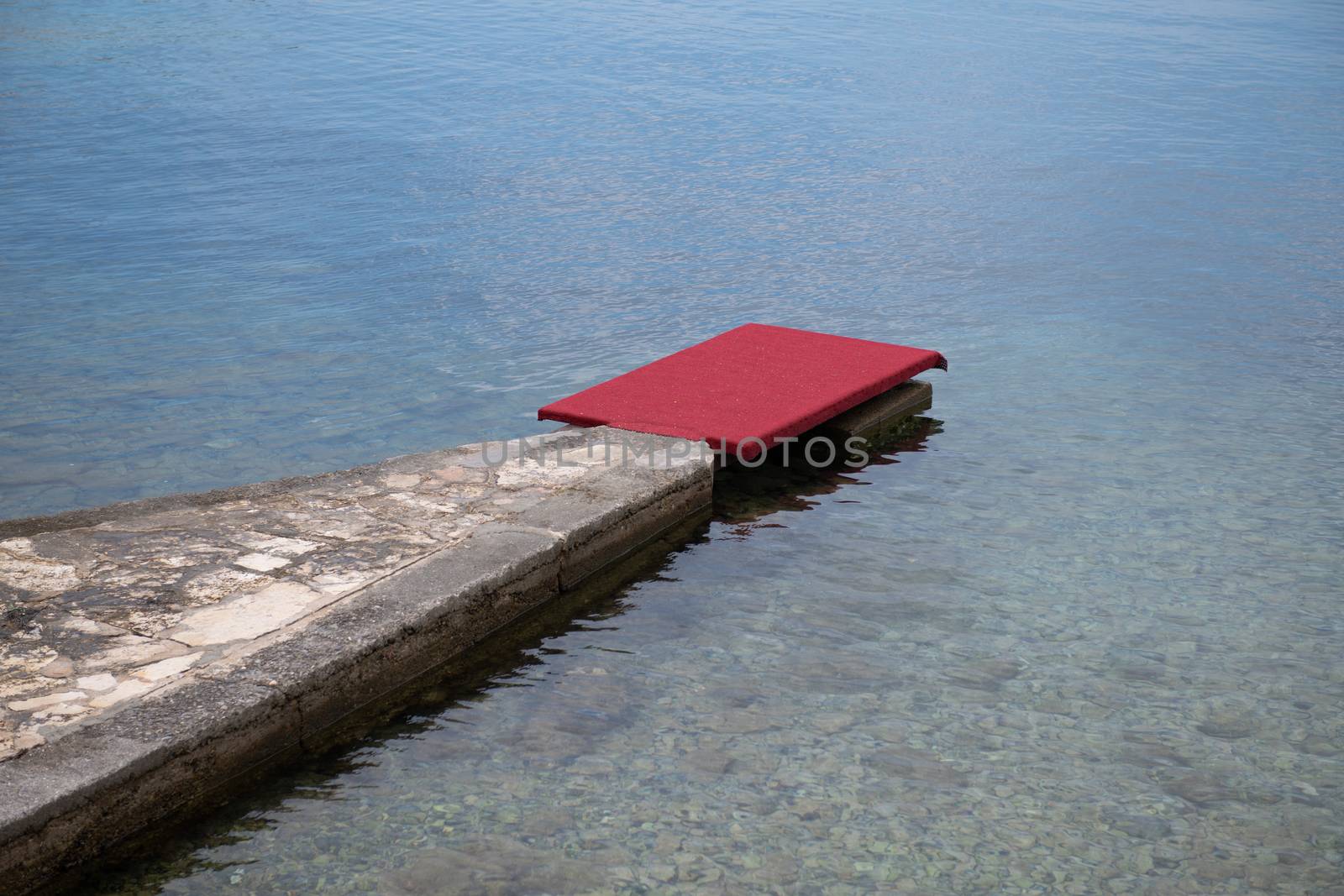 Stone pier with red carpet at waterfront, luxury beach by asafaric