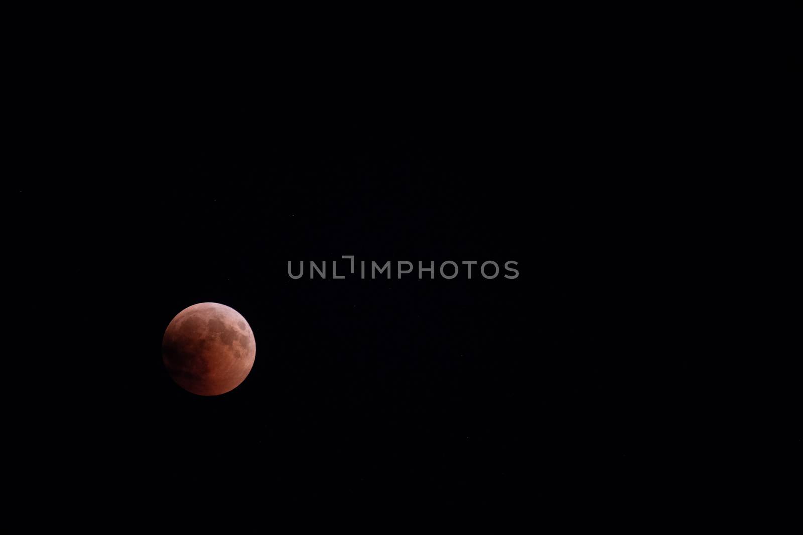 Blood moon during lunar eclipse, blood moon 2018, moon partially lit by sun, copyspace