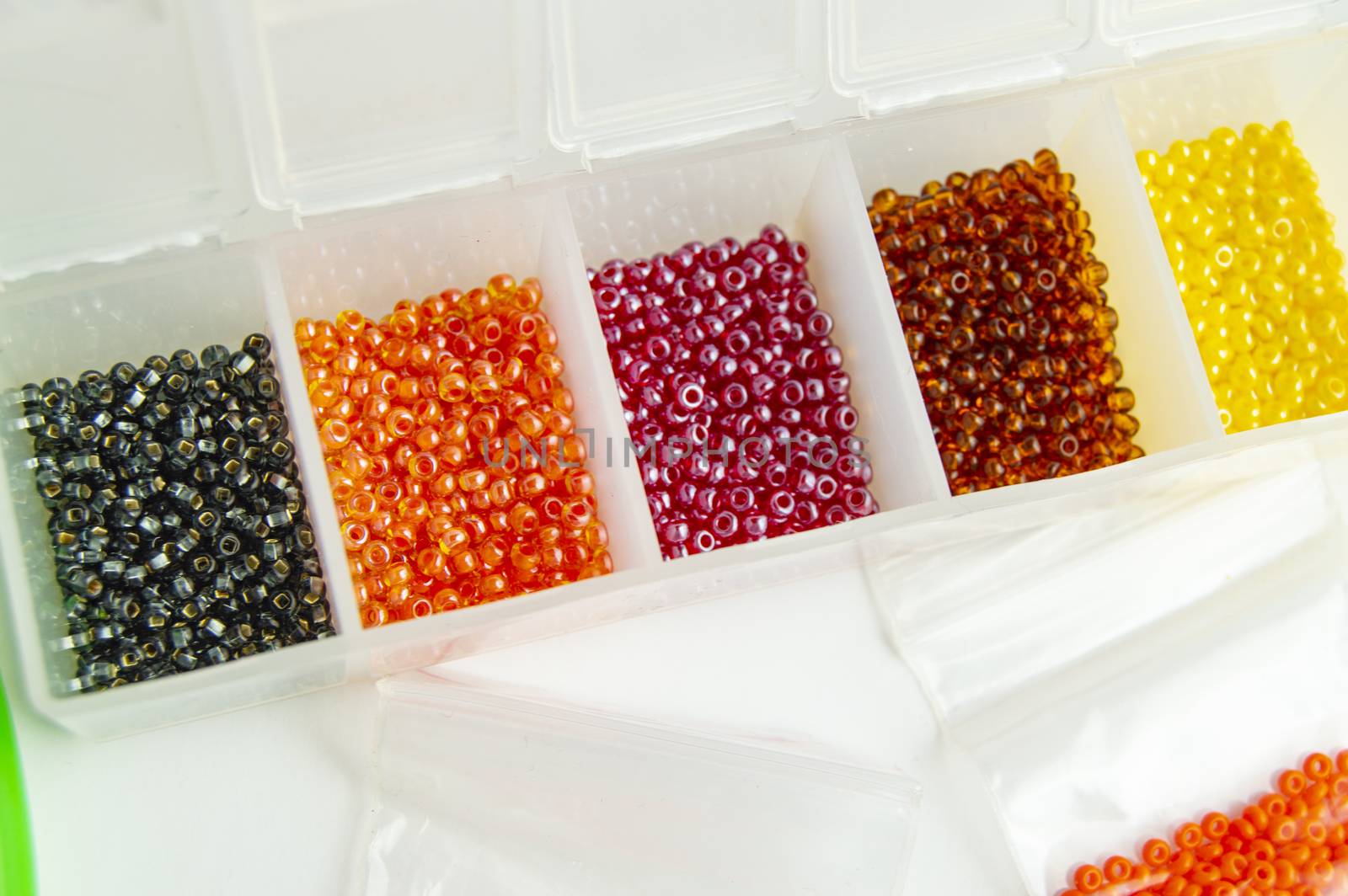 Fletley, plastic box with colorful beads for creativity and hobby, Bright sparkling beads on white background.
