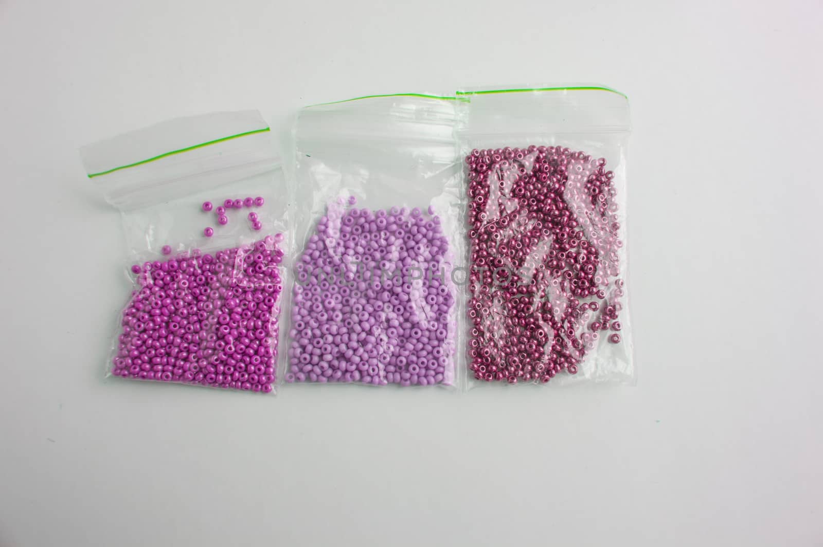 Set of multi-colored beads and beads in a mini plastic bag for embroidery needlework.