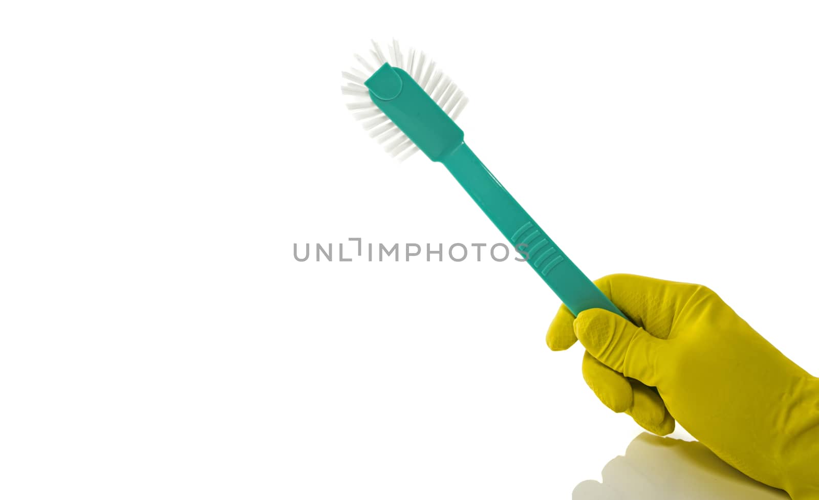 hand with yellow household glove holding a green washing-up brush on a white background