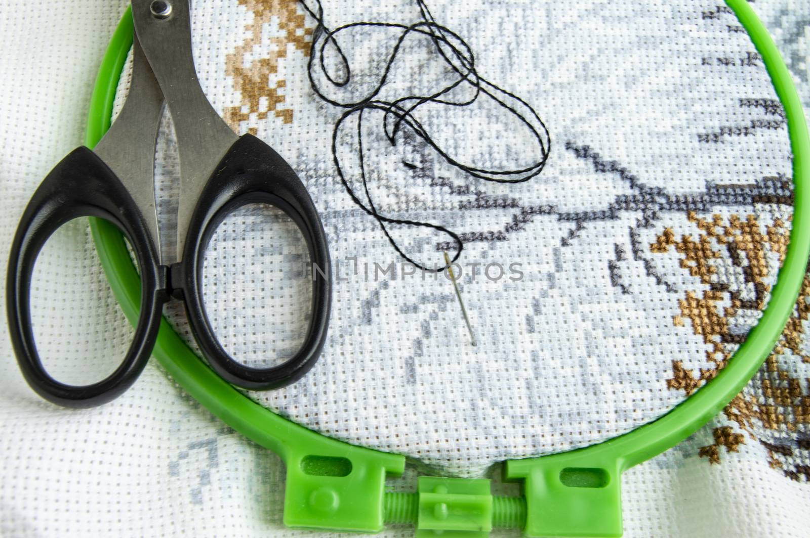 Flat lay canvas with a beautiful pattern of bright sewing threads, scissors and a needle for embroidery close-up.