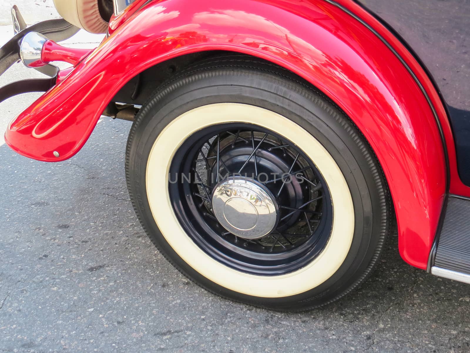 Detail of classic old car, wheel and red fender, with chrome shell.