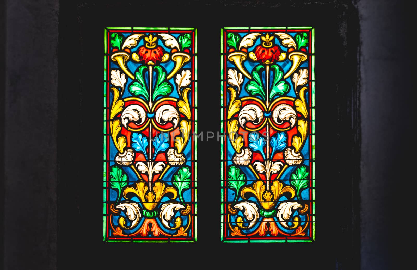 coloured stained glass in a dark background .