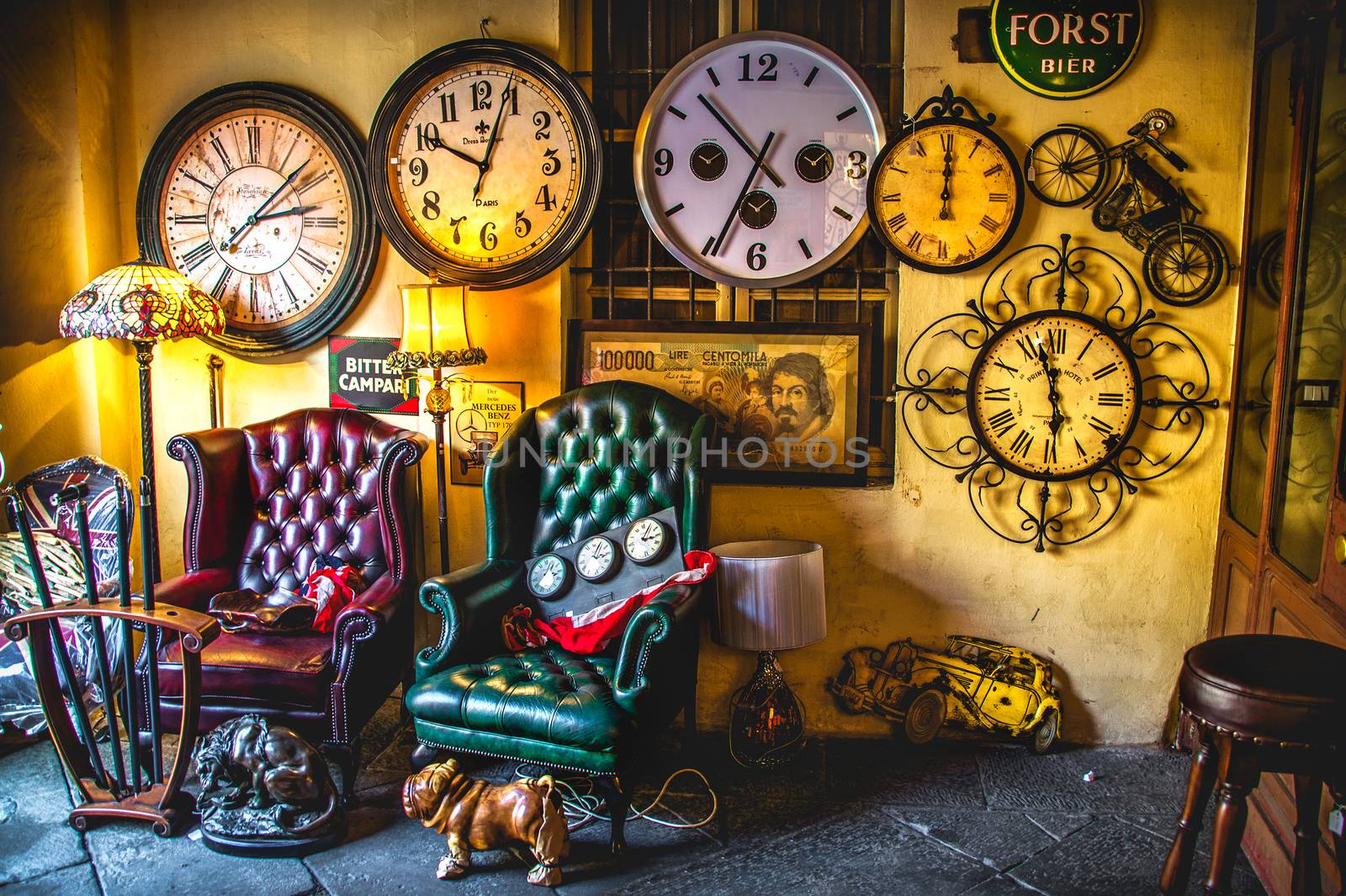 An eccentric vintage living room armchairs with many clocks on the wall background in an antique shop on the Iseo Lake - Brescia - Italy, 16 Feb 2013