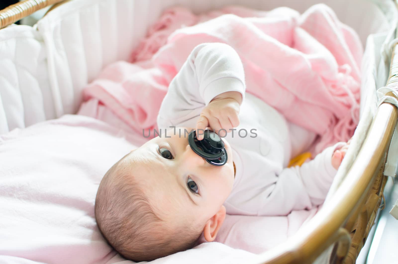 newborn pink cradle hold black pacifier hand