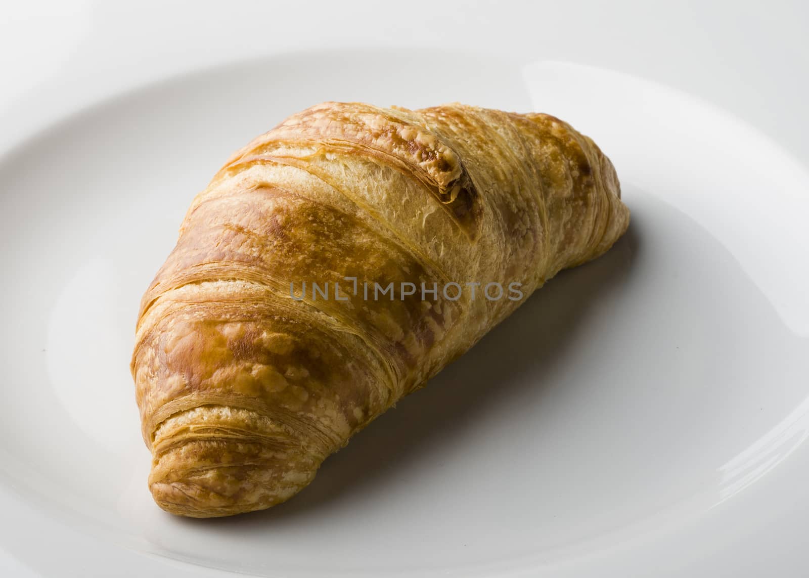Croissant served on a white porcelain plate.