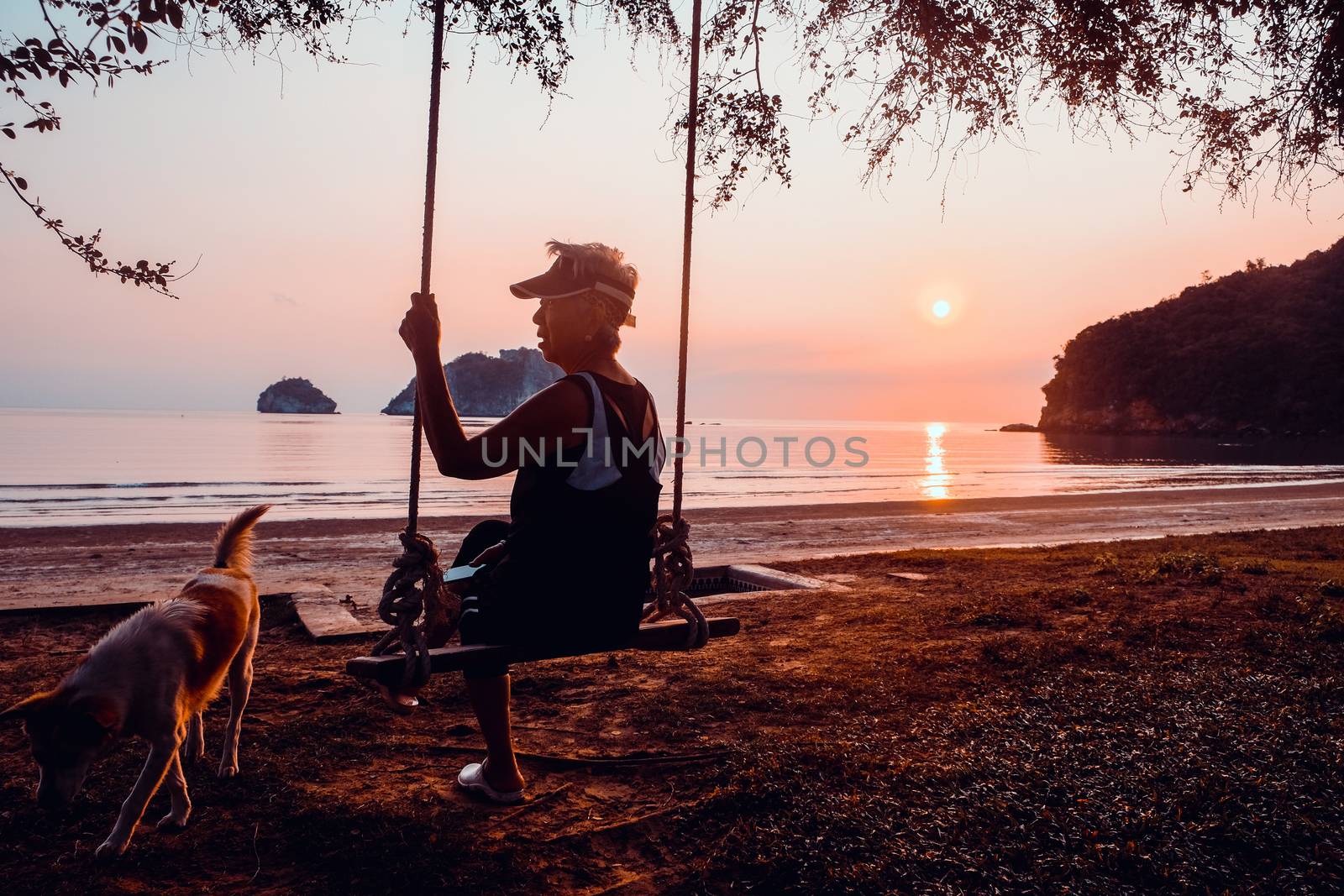 senior woman relaxing on the swings with her dog