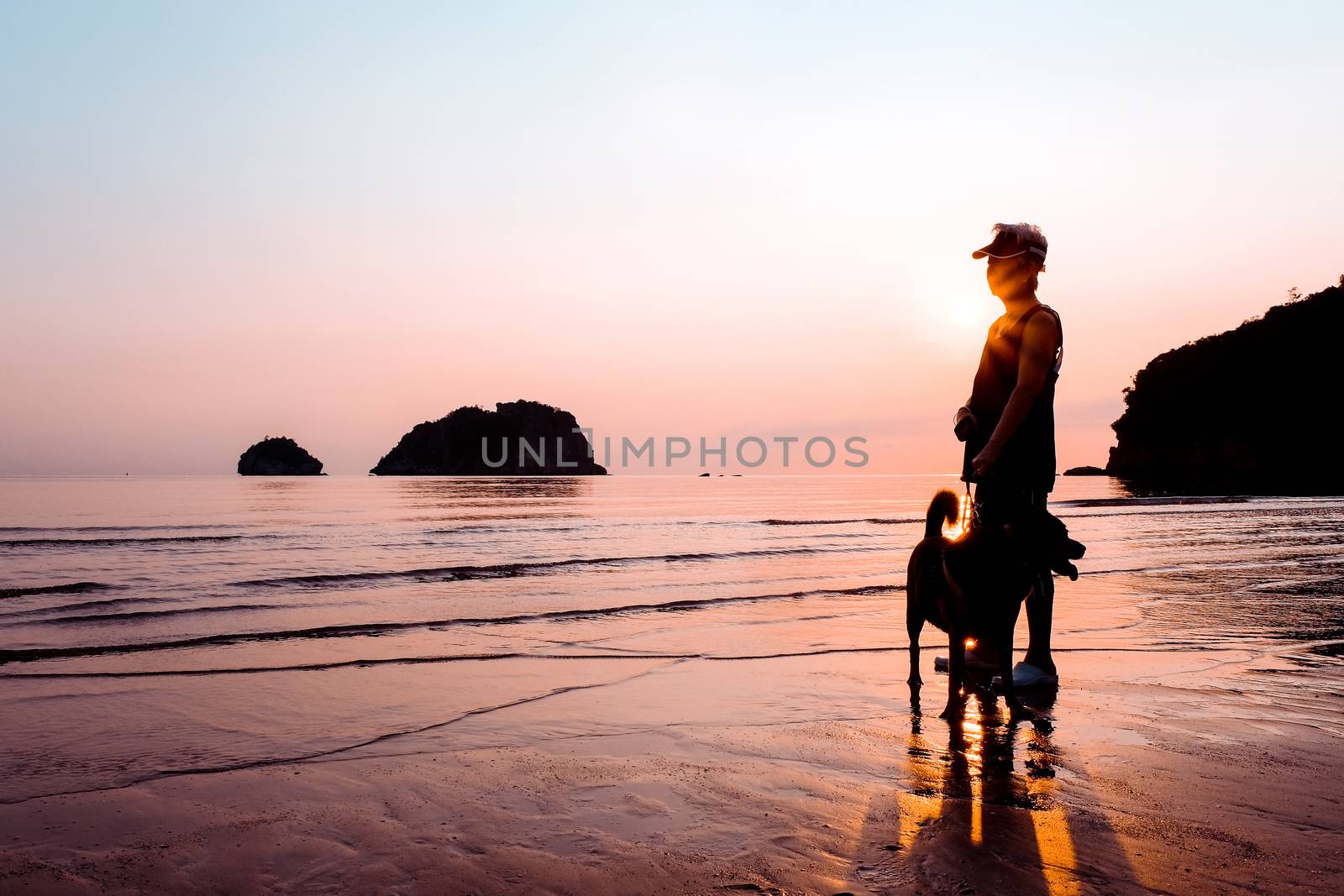 Senior Woman and dog on beach at sunrise