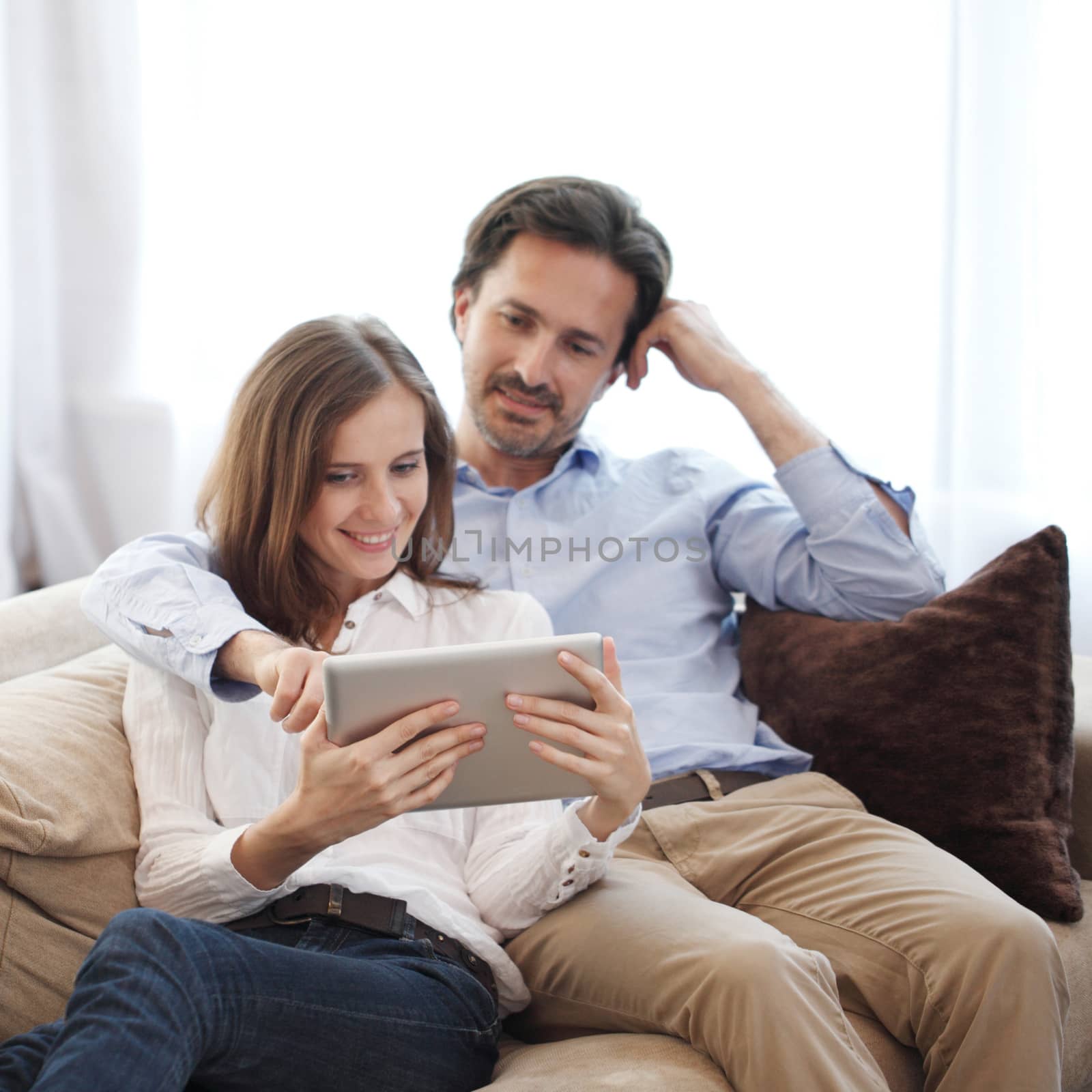 Cheerful couple using digital tablet at home