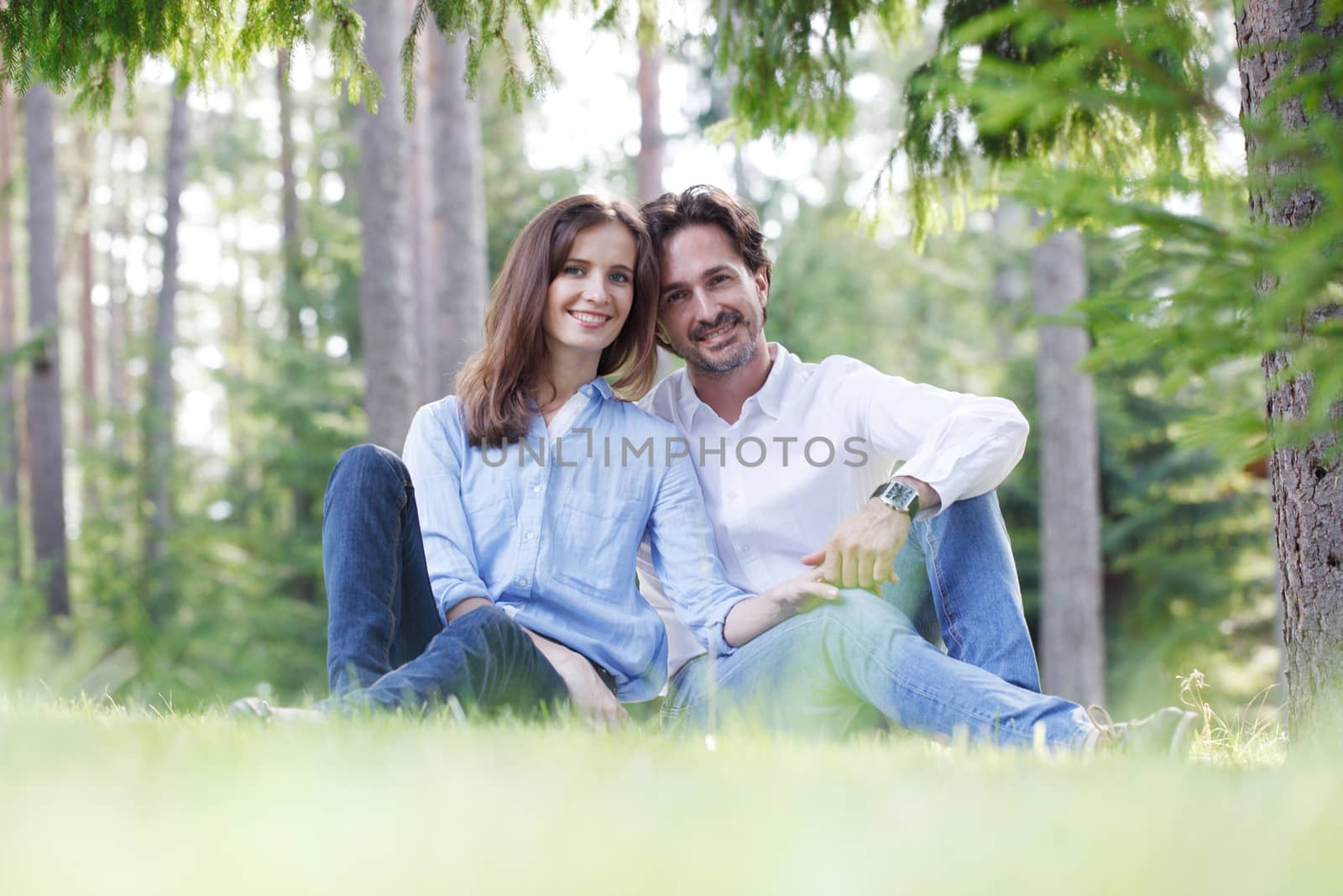 Happy couple sitting on grass in summer park