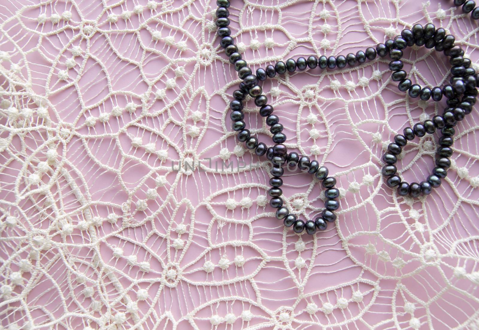 Lay Flat pink background and the gorgeous lace, glittering necklace of black pearls, and stylish bracelet. Beauty and fashion concept.