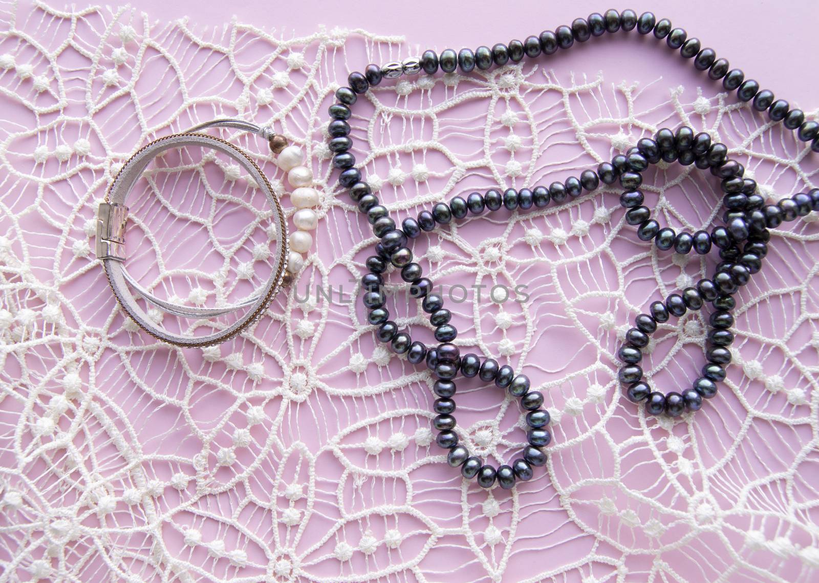 Lay Flat pink background and the gorgeous lace, glittering necklace of black pearls, and stylish bracelet. Beauty and fashion concept by claire_lucia