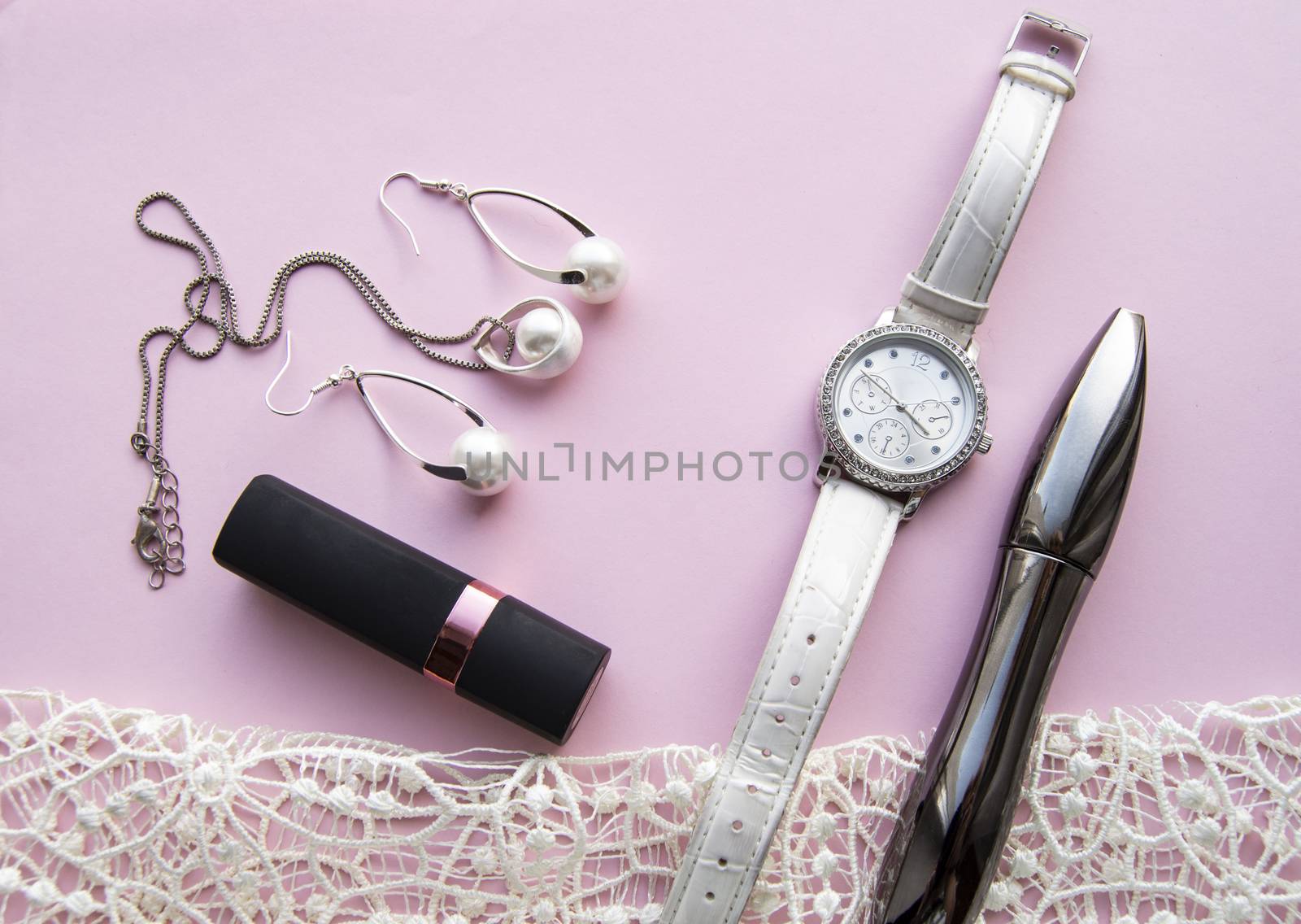flat lay women's accessories collage with stylish watches, earrings and pendant with white pearls, lipstick, mascara on a Lacy pink background by claire_lucia