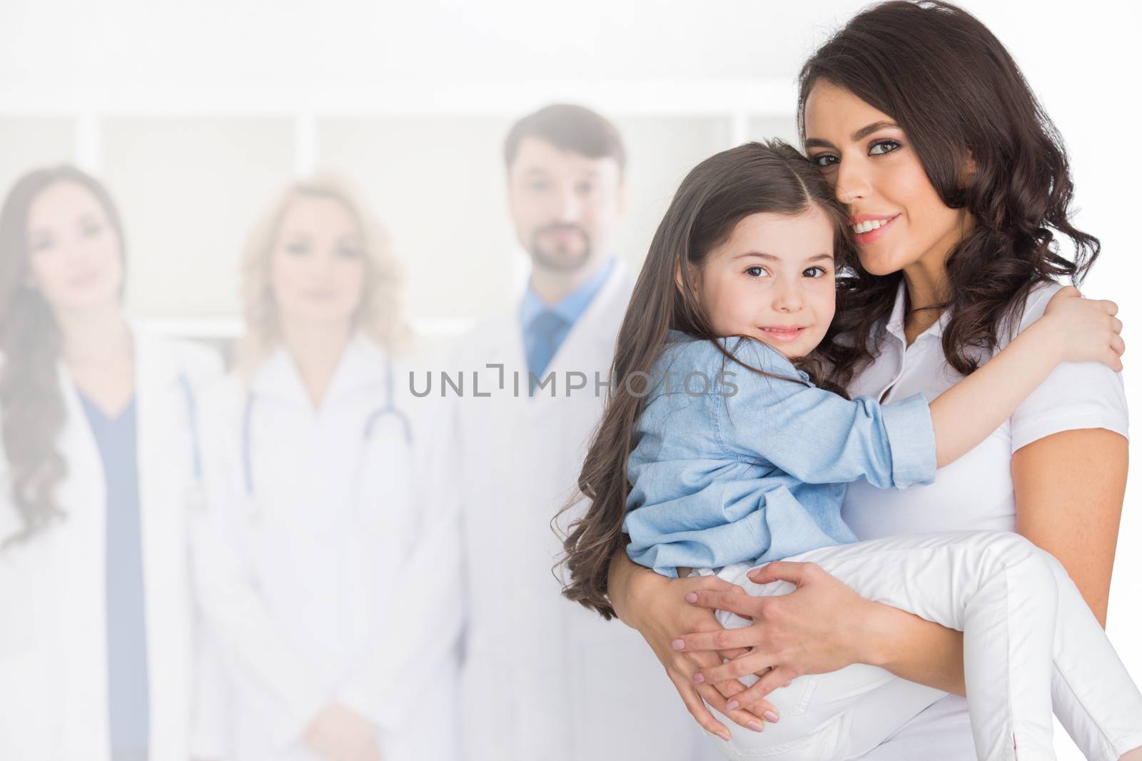 Mother and daughter in medical clinic, team of doctors on background