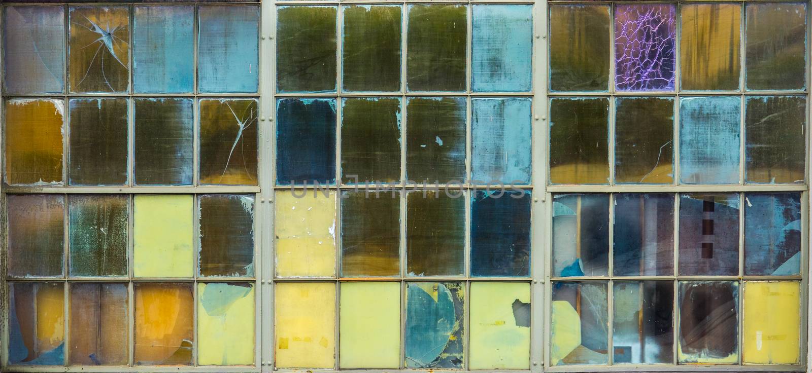 Abstract Background Of Grungy Coloured Panes Of Glass In A Factory Window