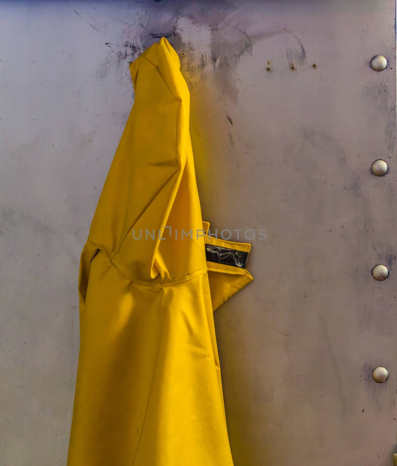 yellow raincoat hanging on a metal wall, Marine background, protective clothing for rainy days by charlottebleijenberg