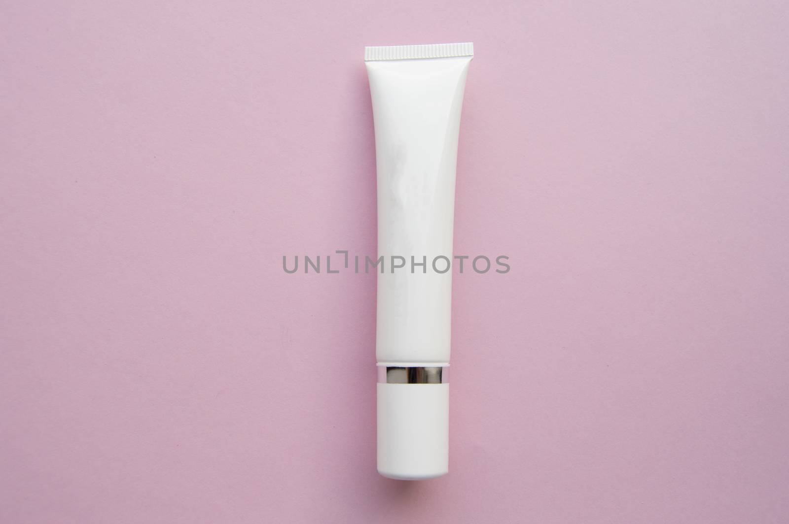 White plastic tube with space for text on pink background, minimalism.