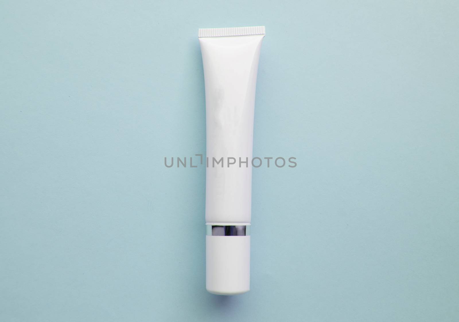 White plastic cream tube with space for text on light blue background, minimalism by claire_lucia