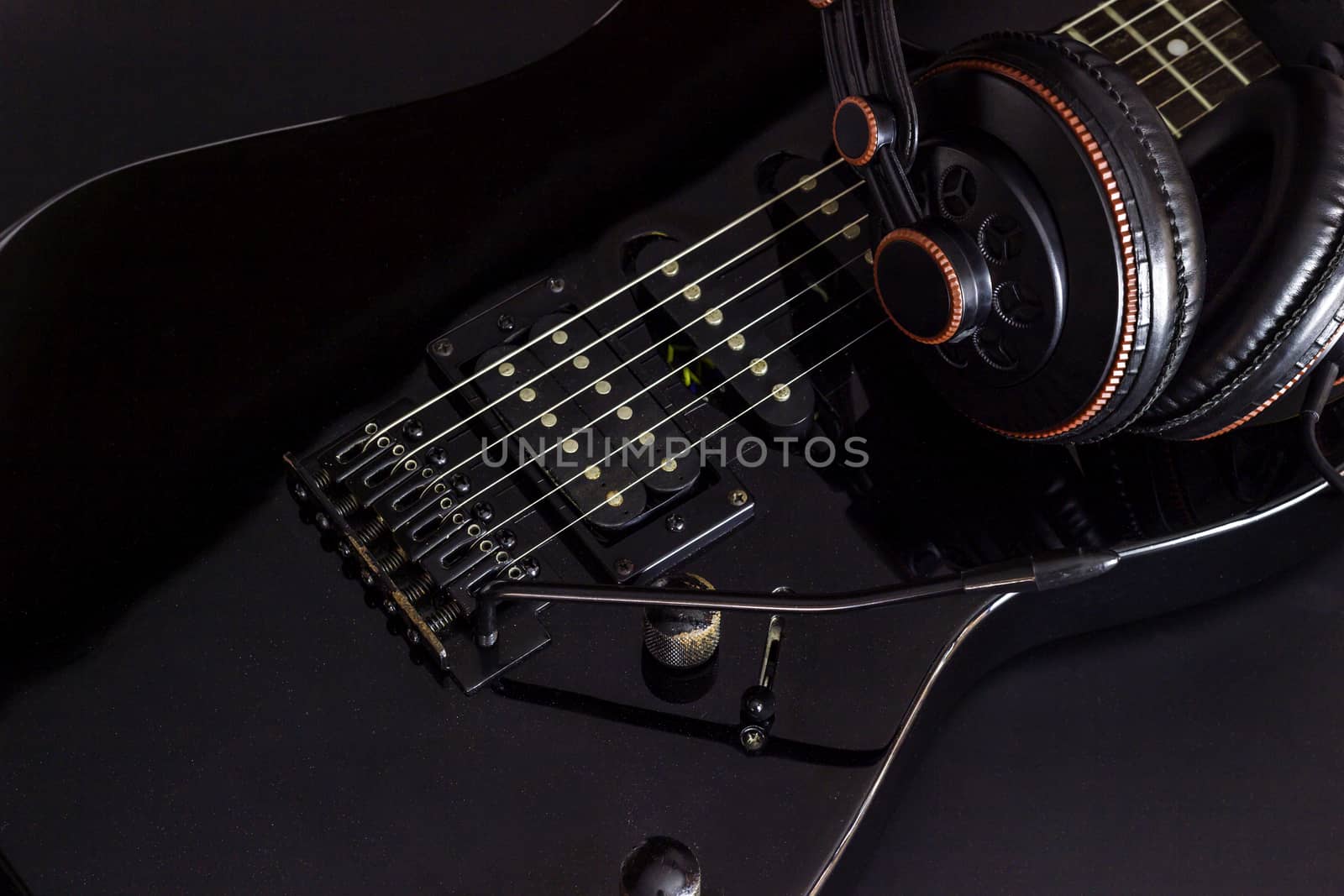 Headphone on black electric guitar in darkness. by SaitanSainam