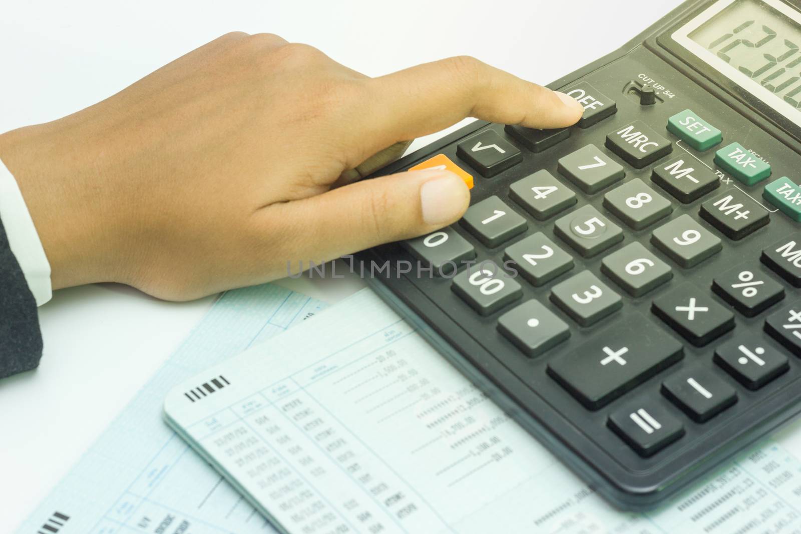 Hand calculate finance. Bank account on white background. by SaitanSainam