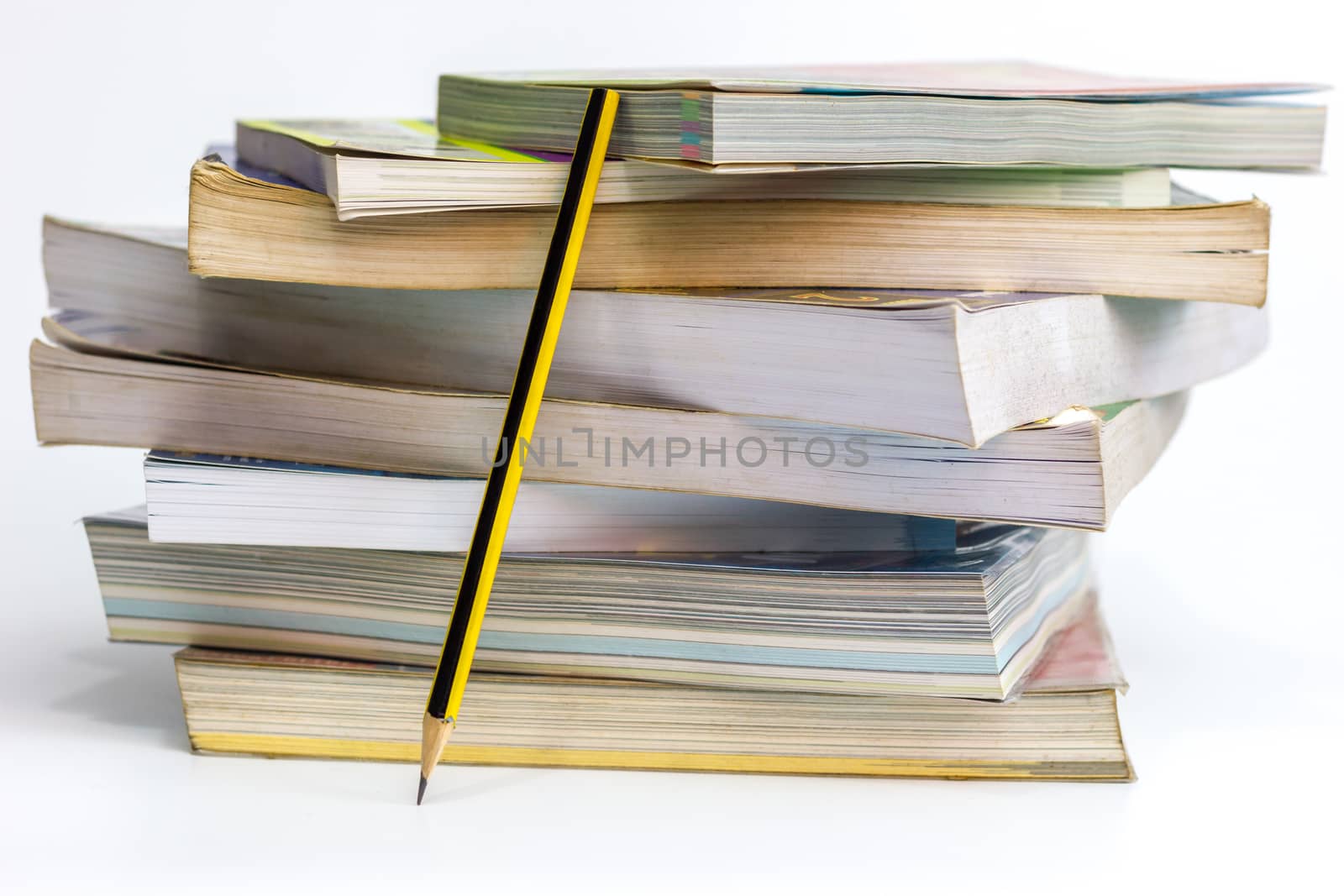 Many old books stacked and Pencil leaning beside the book on white background.