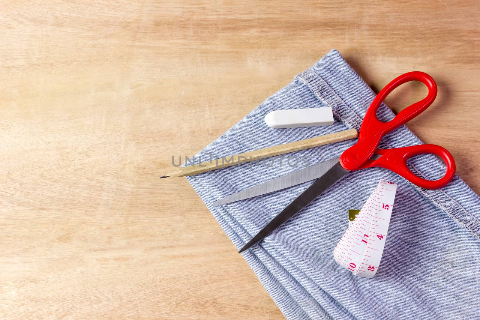 Equipment for jeans fabric cutting on brown wood background.