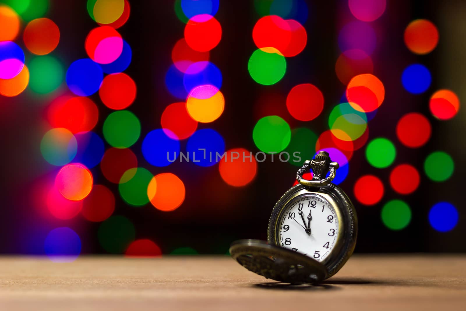 Closeup vintage old clock in the bokeh on brown wood background. The clock is near midnight. Concept Christmas and happy new year or everything related to time.