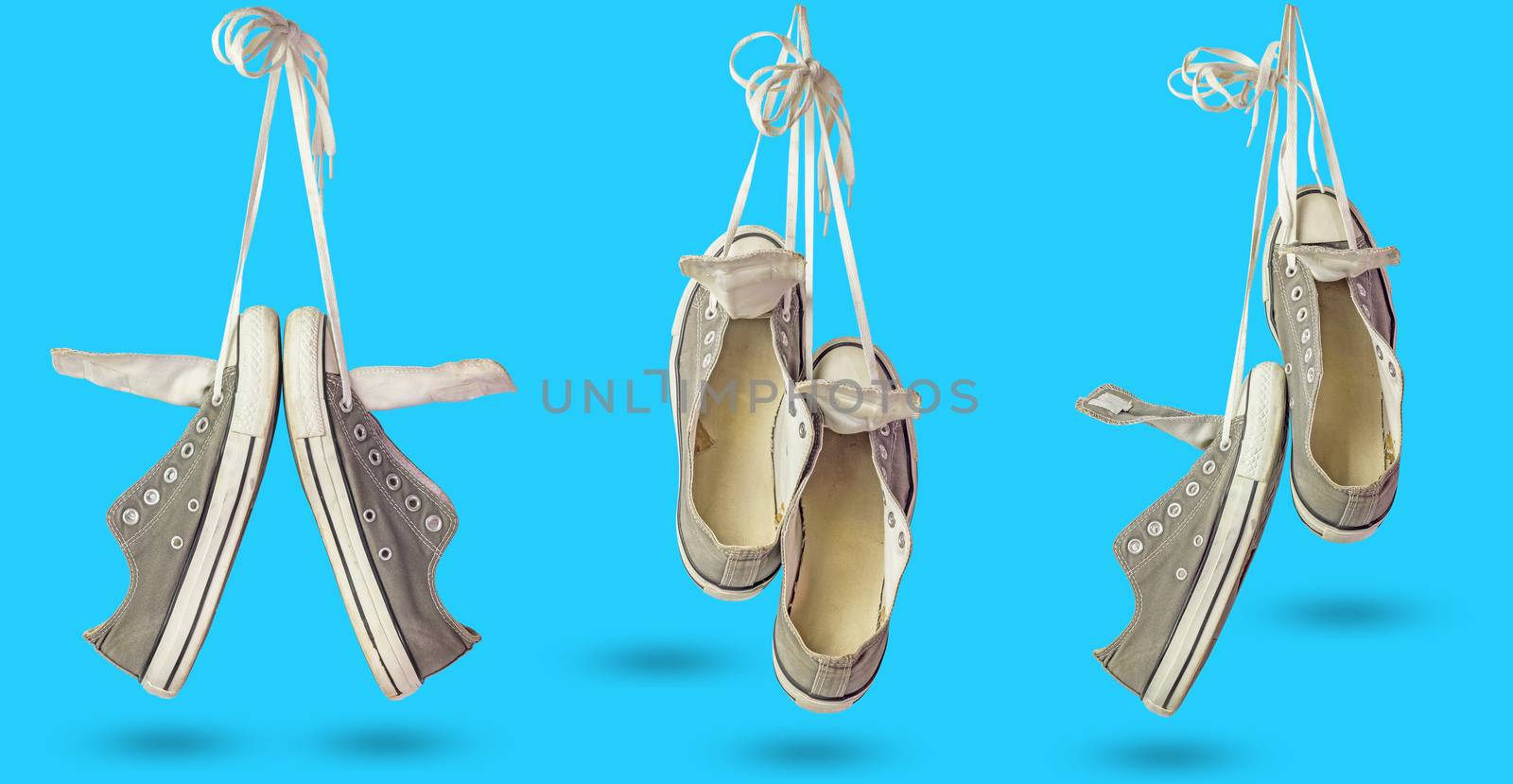 Set of old dirty sneakers hanging on isolate blue background.