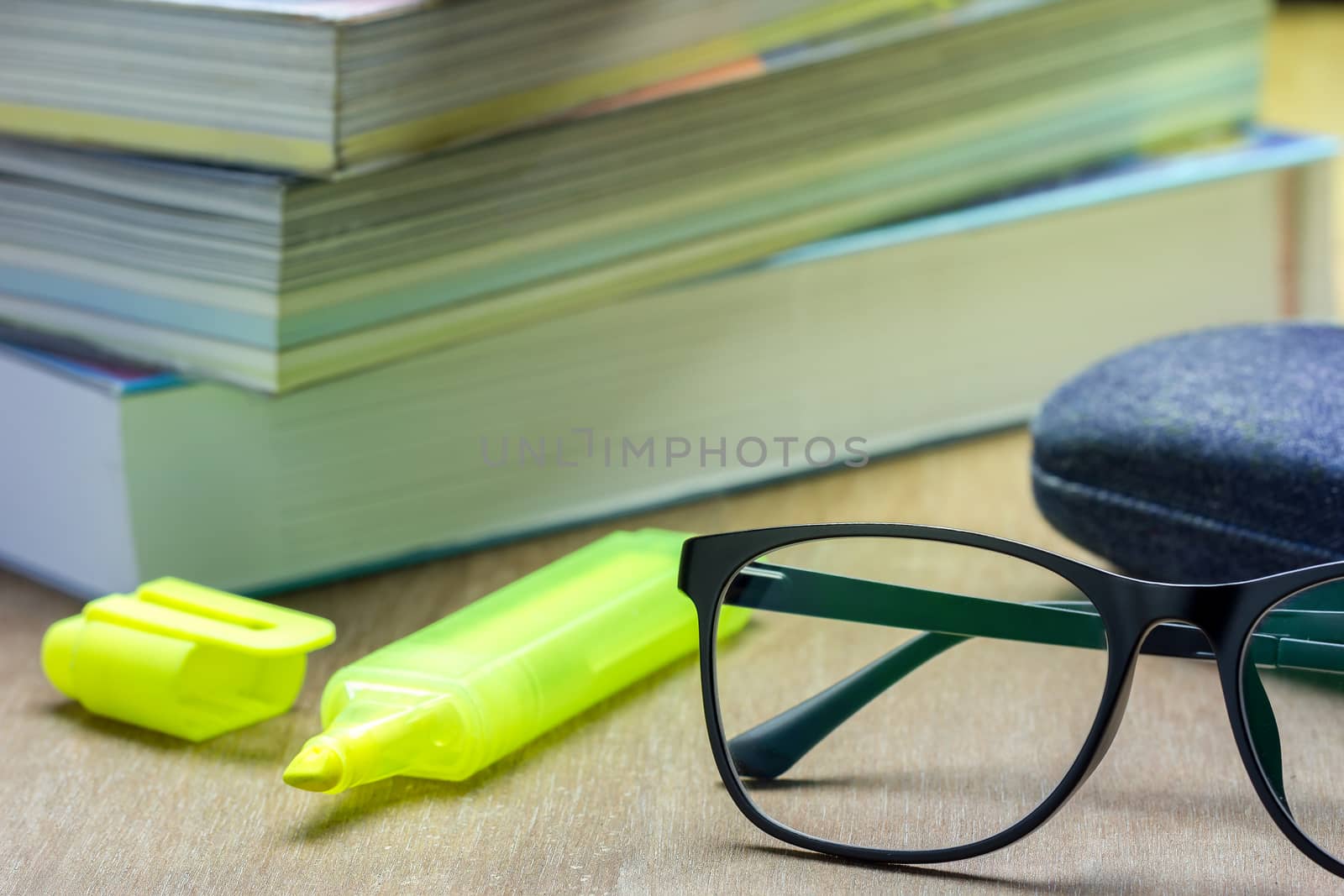 Glasses and old books stacked on brown wood background in the mo by SaitanSainam