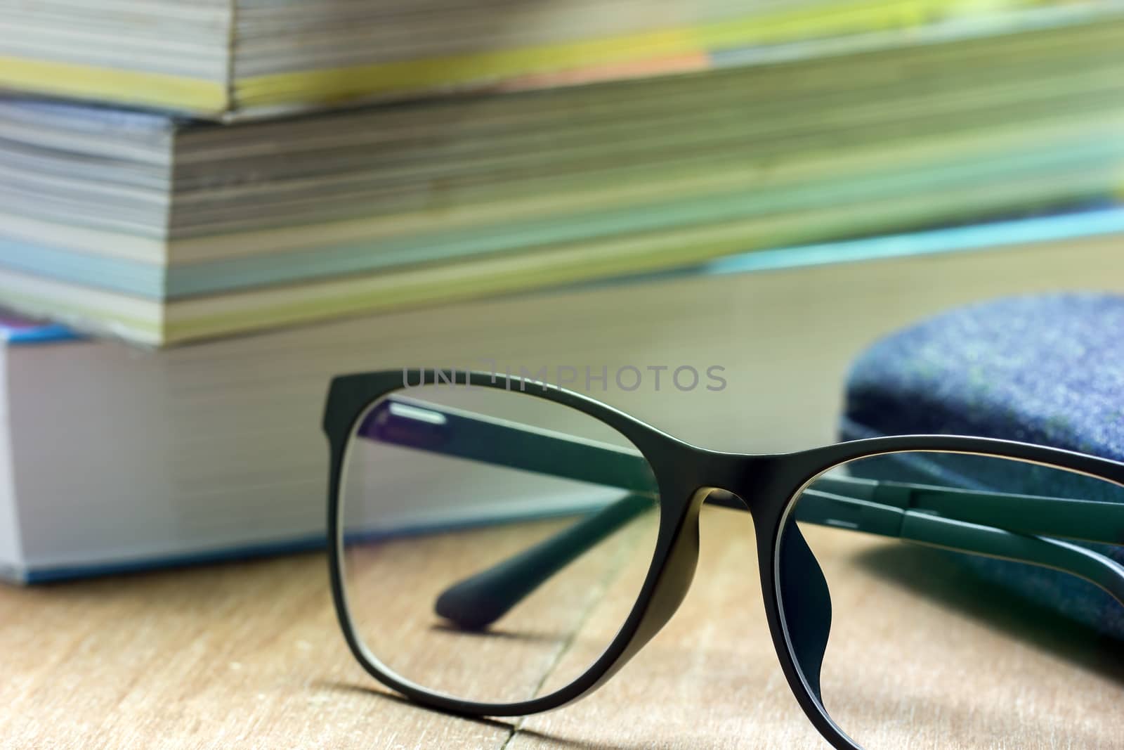 Glasses and old books stacked on brown wood background in the mo by SaitanSainam