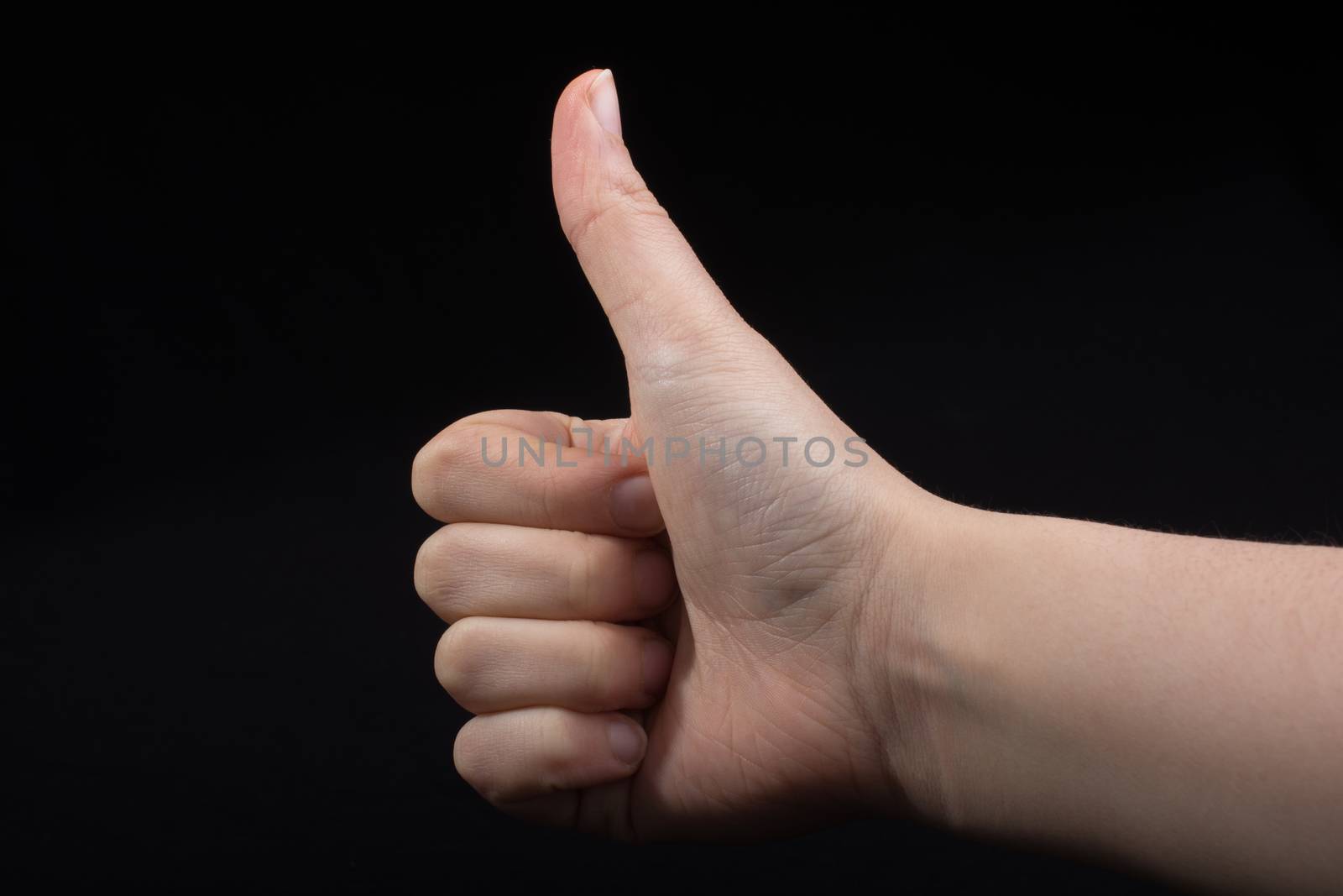 Young hand with thumb up  on black background
