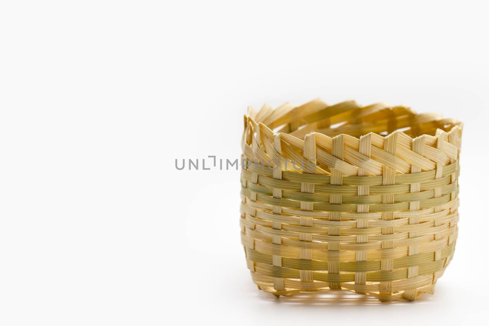 The small basket is made from bamboo, laid on white background.