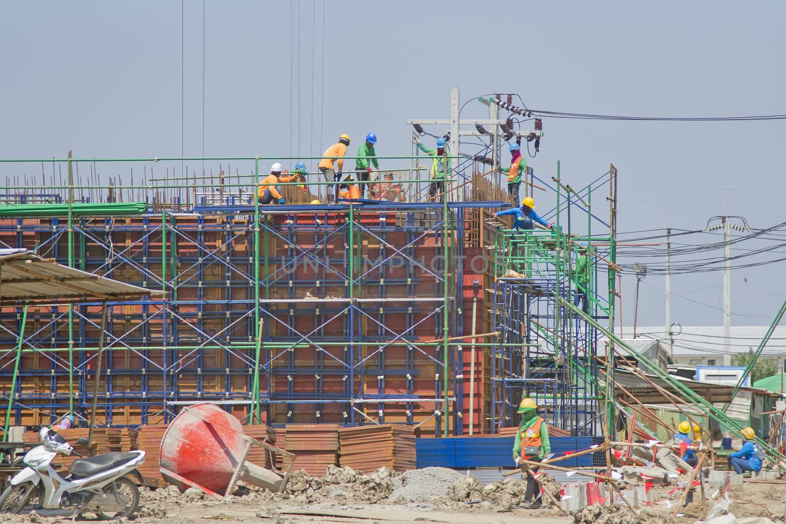 Workers in a baskets are installing sheet, building a factory.