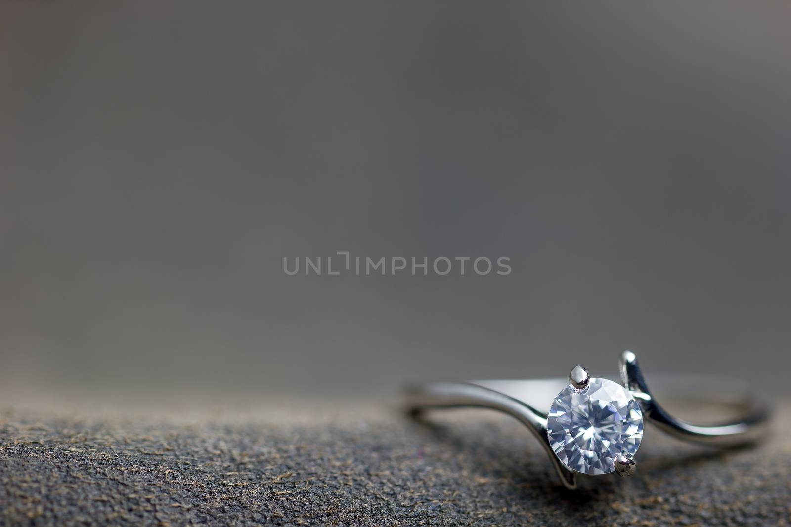 Closeup fake diamond ring placed on brown leather jecket. The co by SaitanSainam