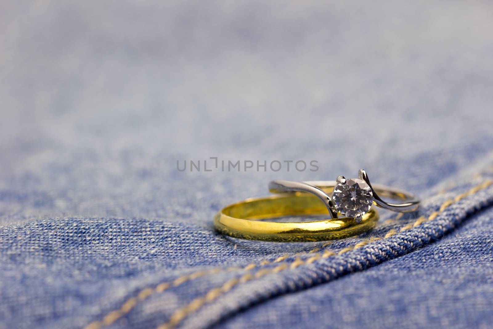 Fake diamond ring and gold ring placed on Jean jecket. The concept of love or marriage. Copy space can be used to write articles about Valentine's Day.