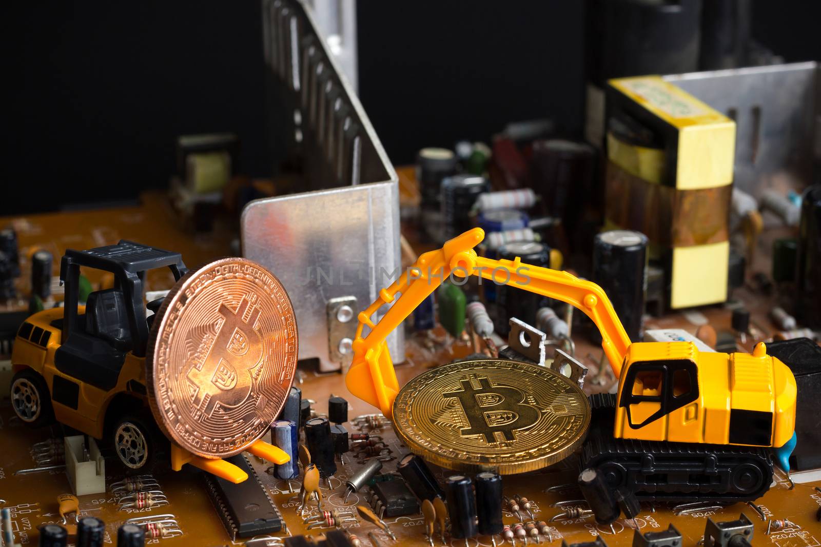 Backhoe and forklift dig bitcoin on mainboard. Concept of bitcoi by SaitanSainam