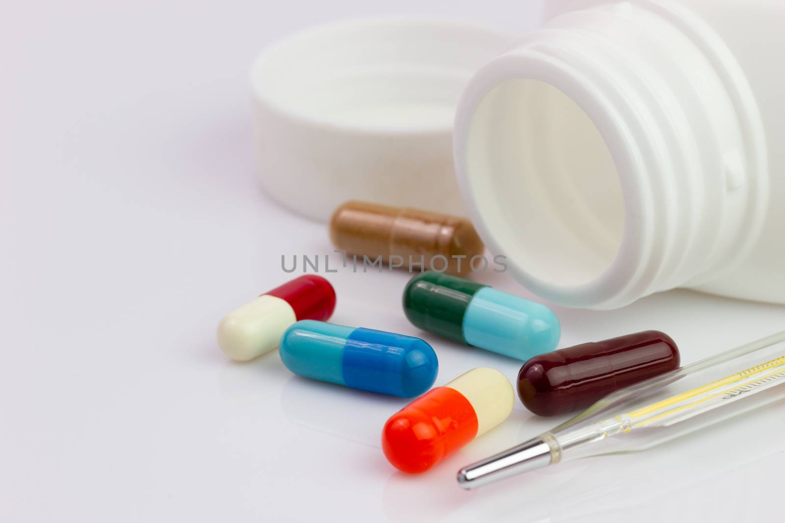 White pill bottle and colorful antibiotic capsule beside the the by SaitanSainam