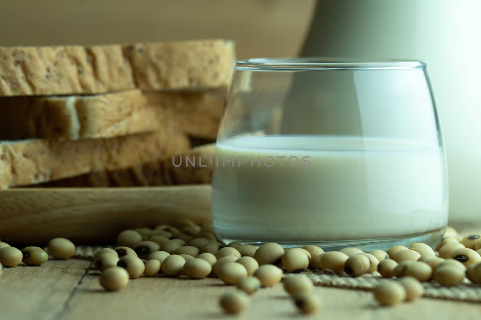 Soybean milk in a glass jug and whole wheat bread in wood disk on table. The concept of healthy breakfast.