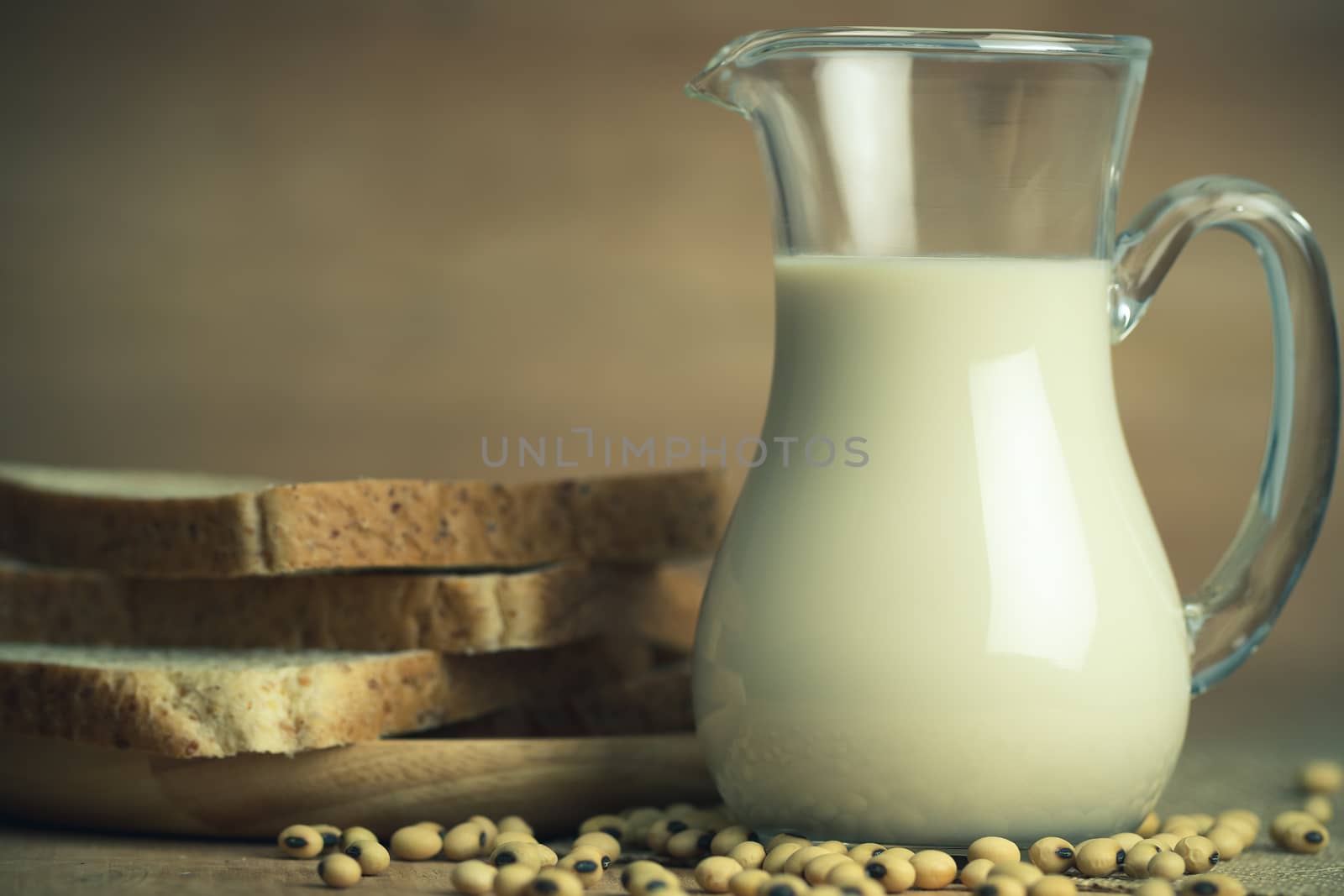 Soybean milk in a glass jug and whole wheat bread in wood disk o by SaitanSainam