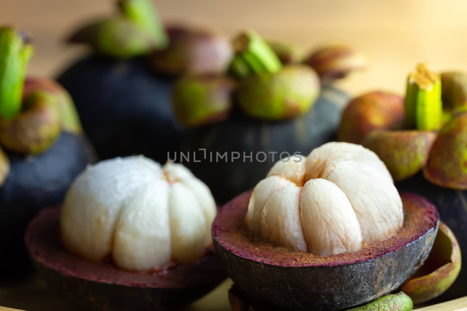 Mangosteen was peeled in a plate on a wooden table. by SaitanSainam