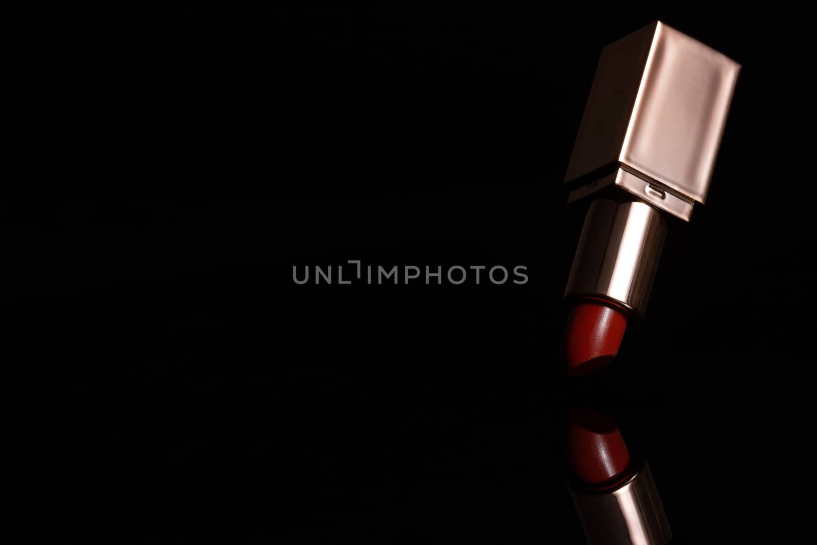 Red lipstick in golden tube and reflection on dark background. C by SaitanSainam