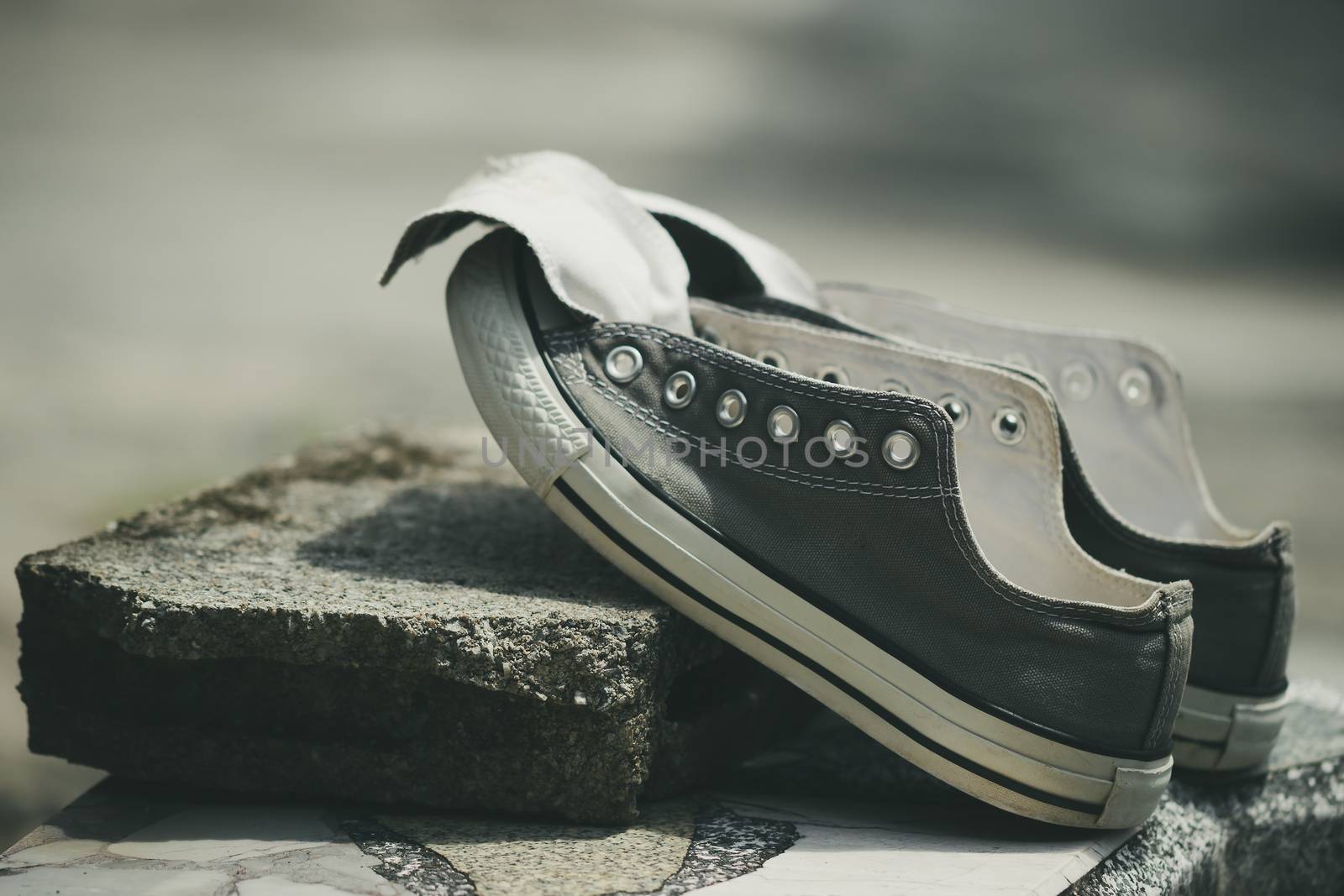 Old sneakers put on a piece of cement in the hot sun.