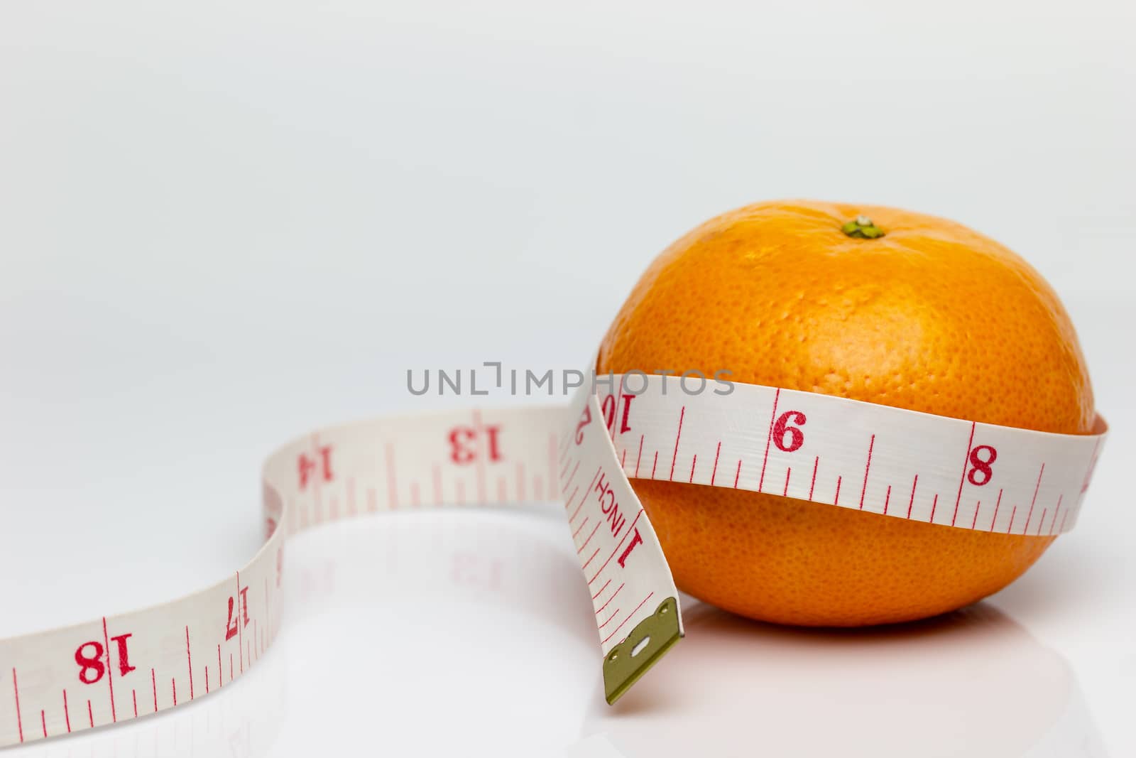 Closeup tangerine was wrapped around it with measuring tape. The concept of love and health care or diet.