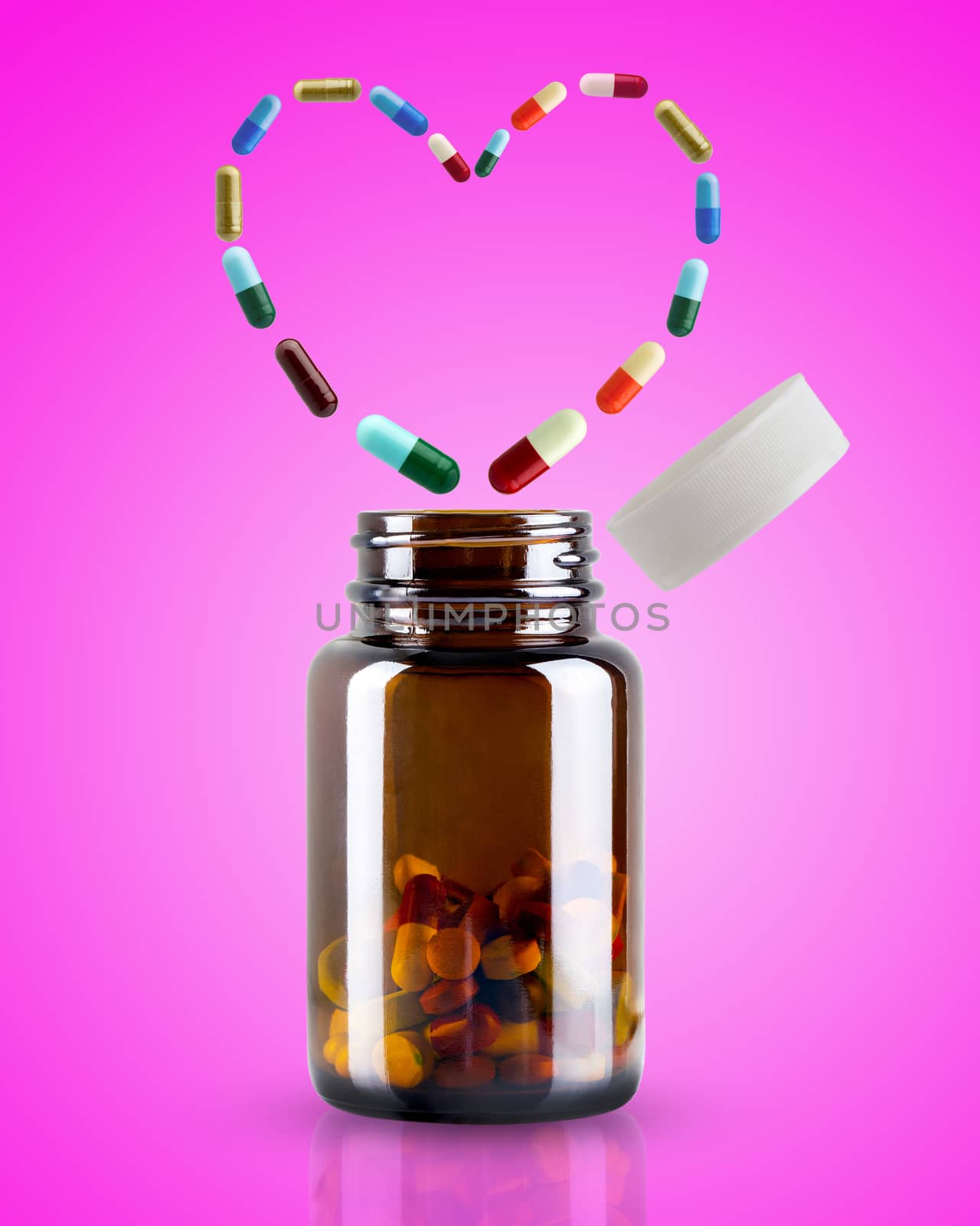 The medicine bottle is opened and the pill is floating in the shape of heart on pink background. Concept of health care.