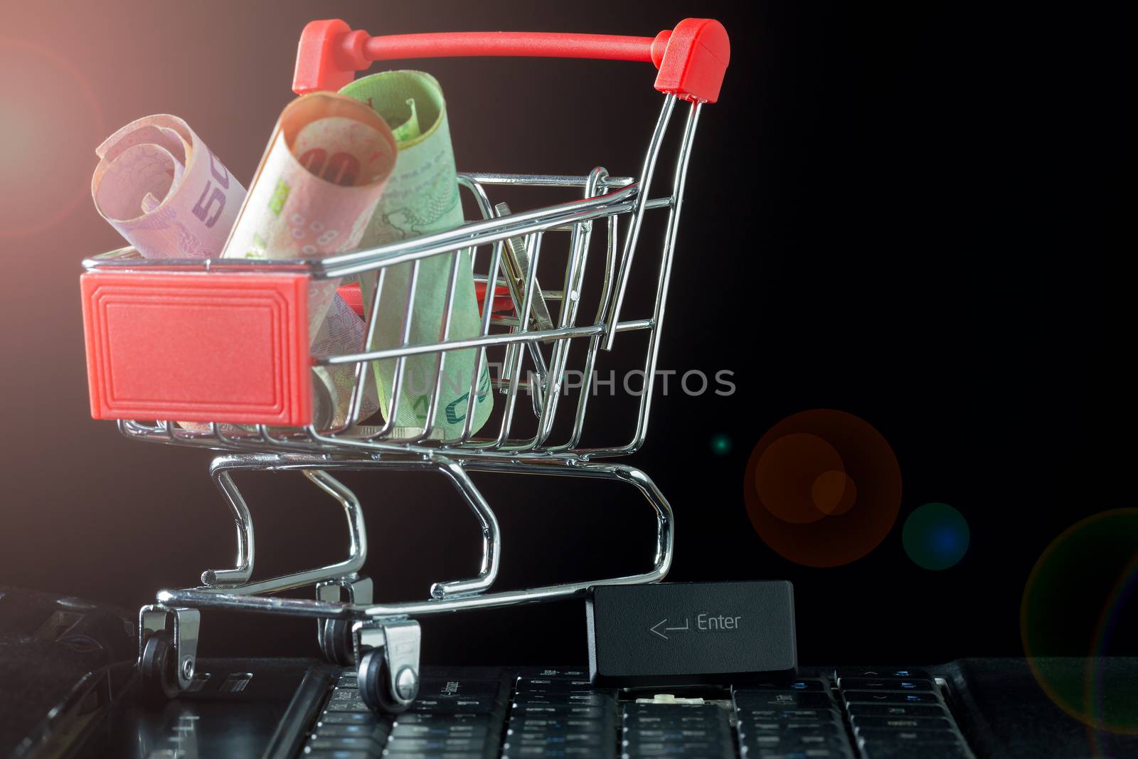 Mini shopping cart with banknote and coin on laptop keyboard in  by SaitanSainam