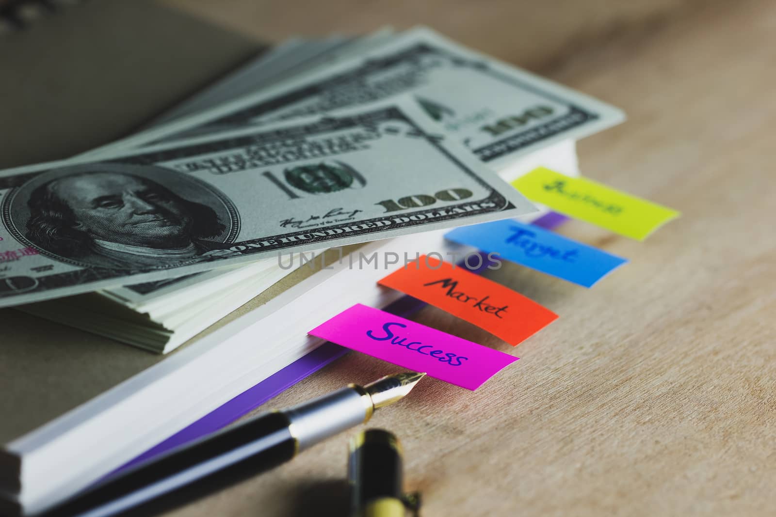 Business notebook and multicolour bookmark with banknote on wood by SaitanSainam