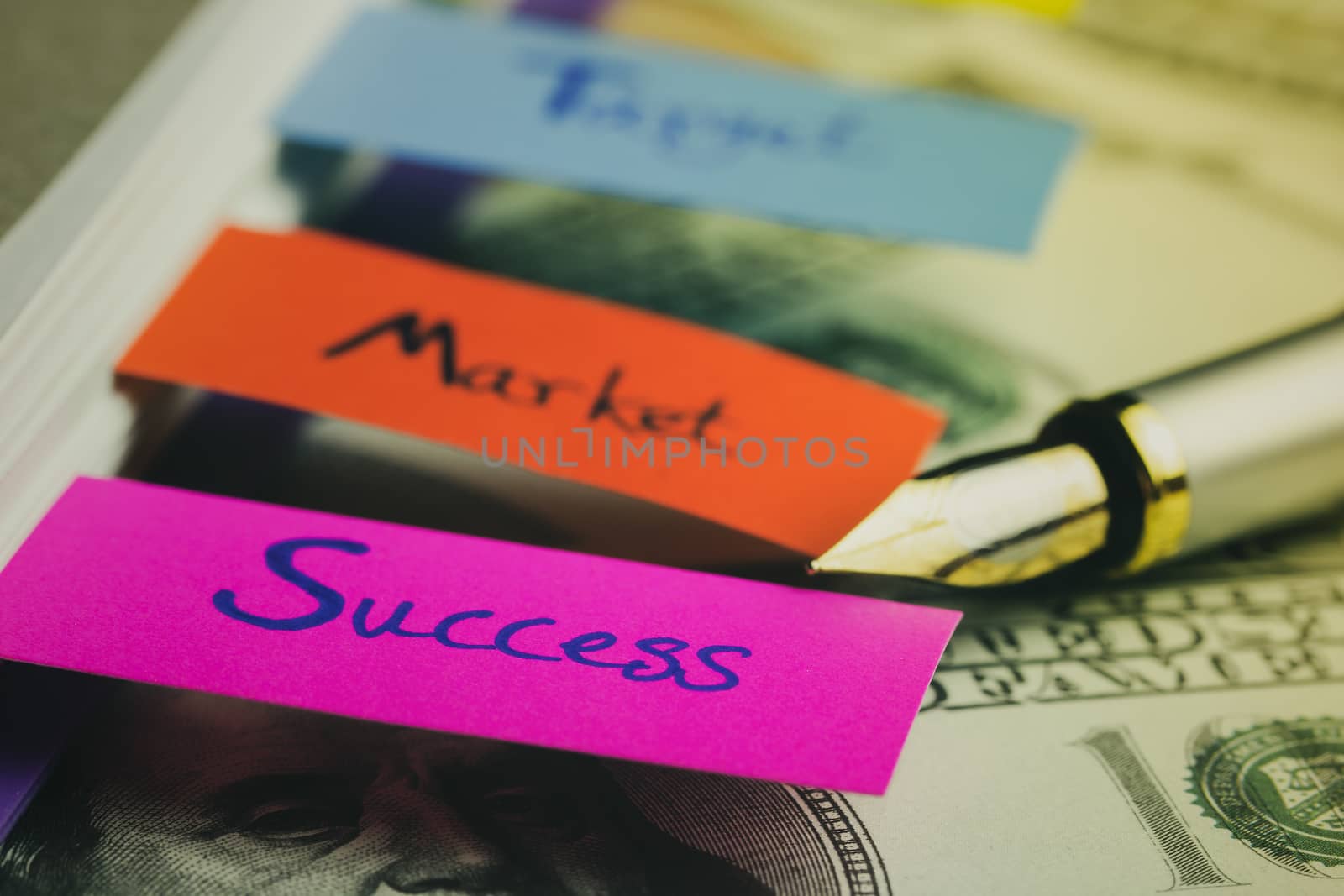 Business notebook and multicolour bookmark with banknote on wood table. Concept of business.